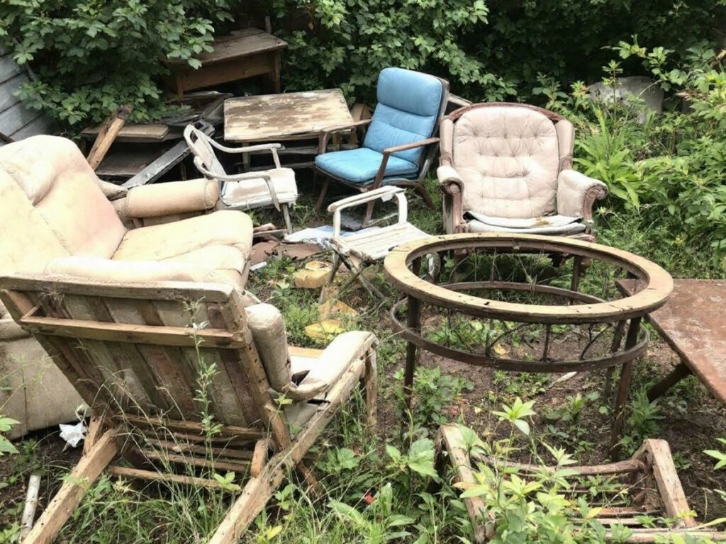 Mobilier abandonné dans un jardin en désordre.